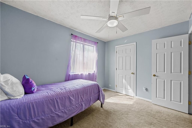 carpeted bedroom featuring ceiling fan, a textured ceiling, and baseboards