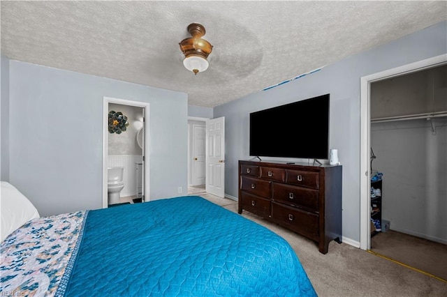 carpeted bedroom with baseboards, ensuite bath, ceiling fan, a closet, and a textured ceiling