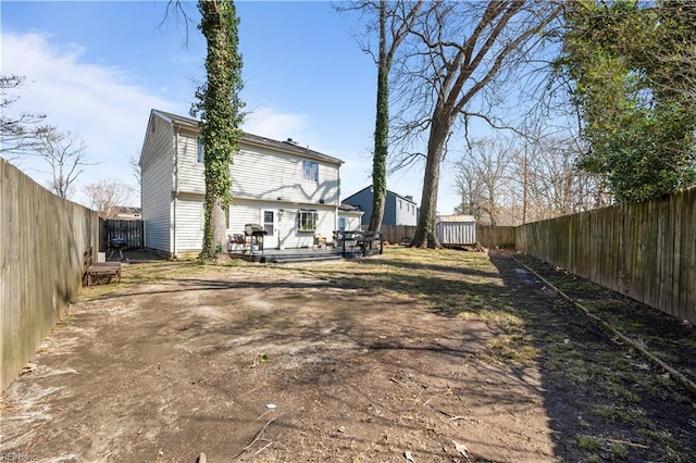 rear view of house with a deck, an outdoor structure, a fenced backyard, and a shed