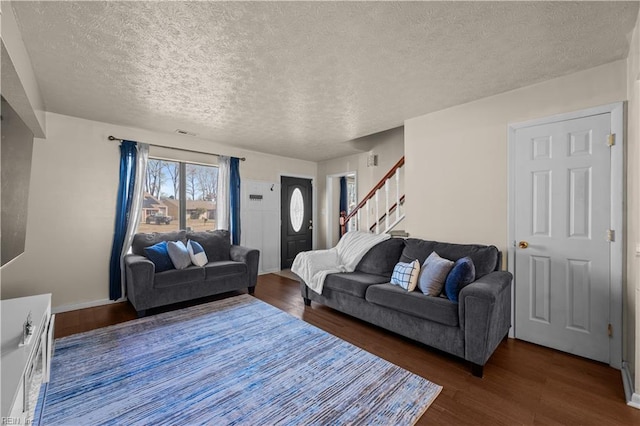 living area with visible vents, baseboards, stairway, wood finished floors, and a textured ceiling