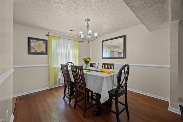 dining space featuring baseboards, wood-type flooring, a textured ceiling, and a chandelier