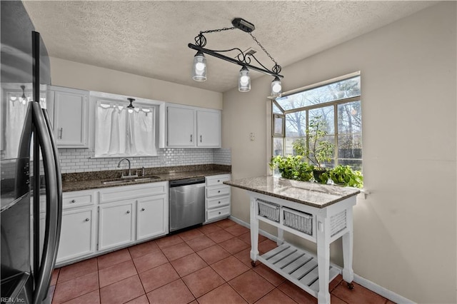 kitchen with tasteful backsplash, stainless steel dishwasher, freestanding refrigerator, white cabinets, and a sink