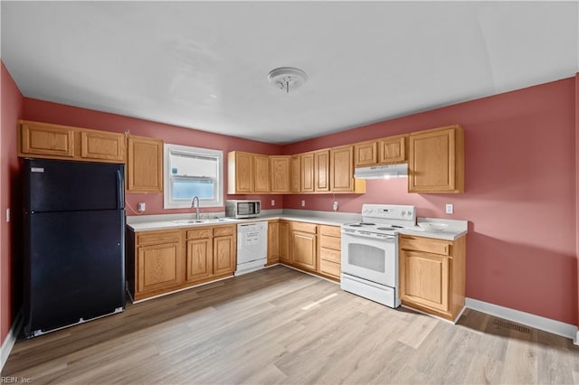 kitchen with under cabinet range hood, white appliances, light countertops, and a sink