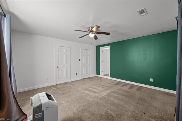 unfurnished bedroom featuring visible vents, two closets, a ceiling fan, carpet flooring, and baseboards