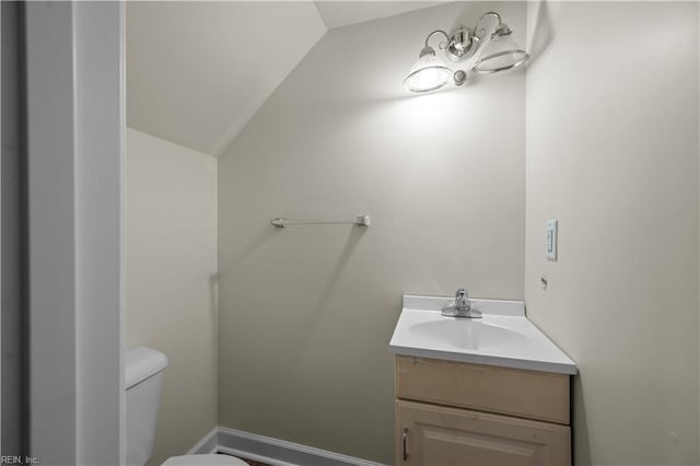 half bathroom with toilet, vanity, and lofted ceiling