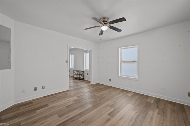 empty room featuring a ceiling fan, baseboards, and wood finished floors