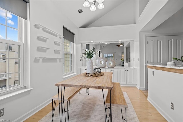 dining space featuring baseboards, visible vents, high vaulted ceiling, and light wood-style floors