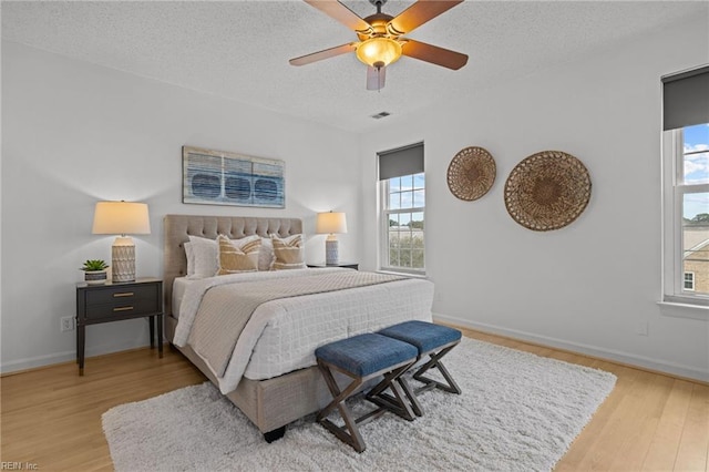 bedroom featuring multiple windows, a textured ceiling, and wood finished floors