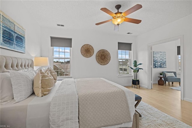 bedroom with visible vents, multiple windows, and wood finished floors