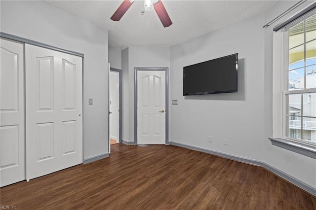 unfurnished bedroom with baseboards, wood finished floors, a closet, a textured ceiling, and a ceiling fan