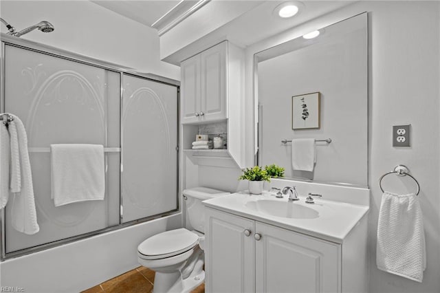 bathroom featuring tile patterned floors, toilet, vanity, and bath / shower combo with glass door