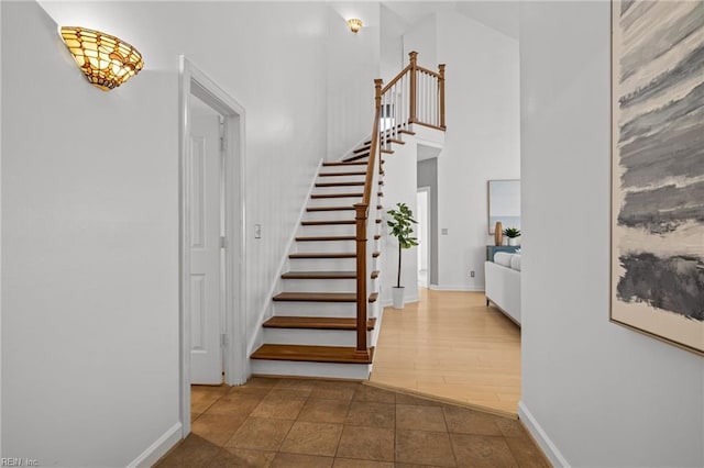 stairway with baseboards, a high ceiling, and tile patterned flooring