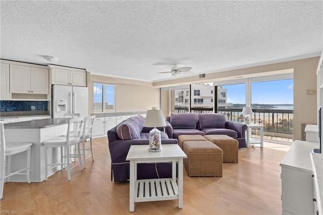 living area with plenty of natural light, light wood-type flooring, and a ceiling fan