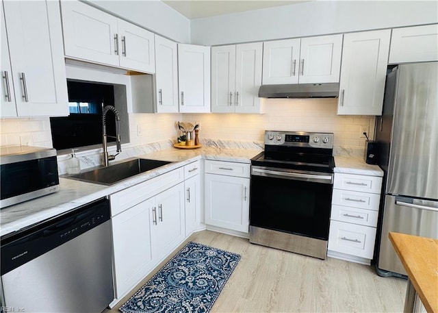 kitchen featuring under cabinet range hood, light countertops, stainless steel appliances, white cabinetry, and a sink