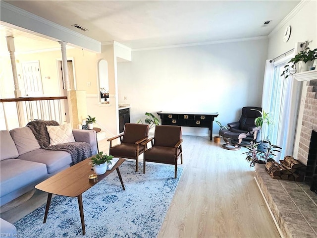 living room featuring visible vents, ornamental molding, a fireplace, and wood finished floors