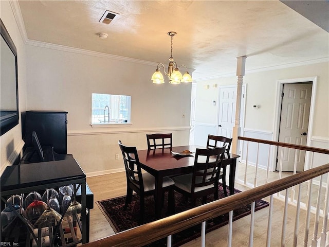 dining area with visible vents, wood finished floors, an inviting chandelier, crown molding, and baseboards