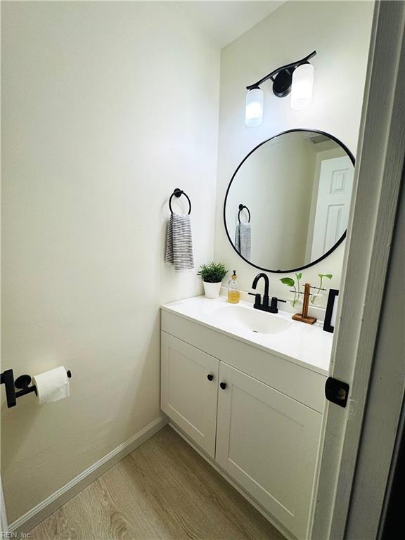 bathroom featuring vanity, wood finished floors, and baseboards