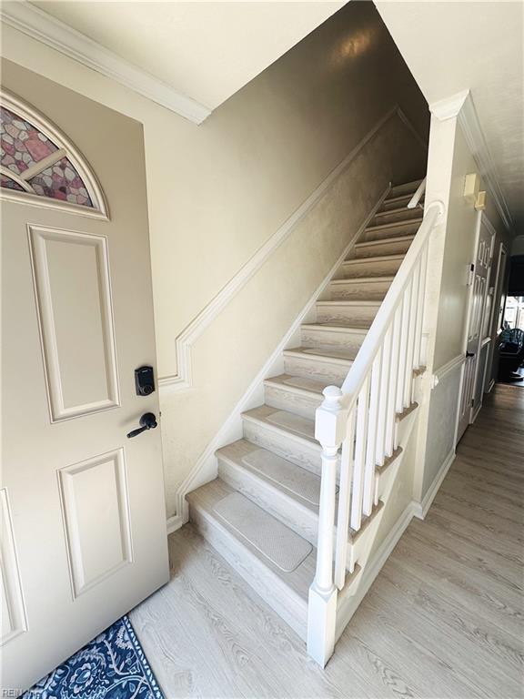 stairway featuring wood finished floors and ornamental molding