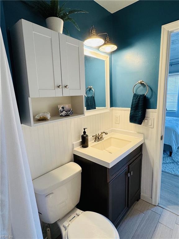 bathroom featuring a wainscoted wall, ensuite bathroom, toilet, and vanity