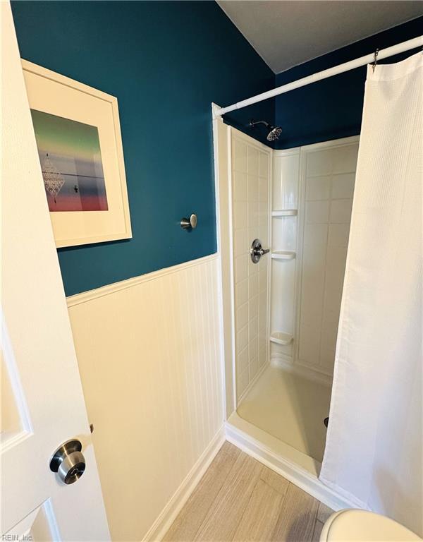 full bathroom featuring wainscoting, a shower with shower curtain, and wood finished floors