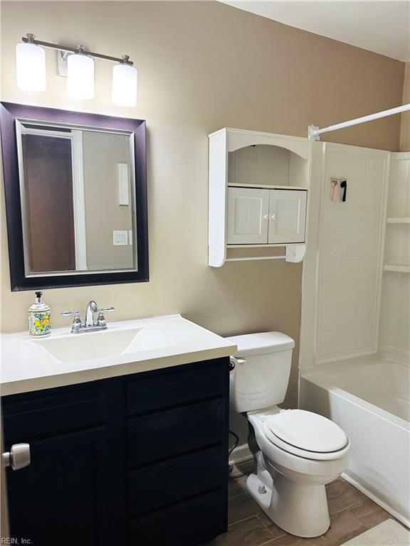 bathroom featuring vanity, washtub / shower combination, toilet, and wood finished floors