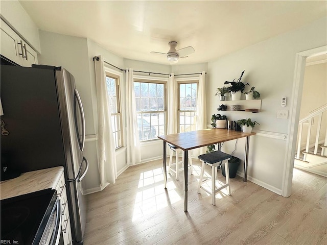 dining space featuring baseboards, light wood-style floors, and a ceiling fan