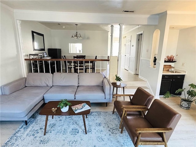 living area featuring visible vents, light wood-type flooring, decorative columns, and ornamental molding