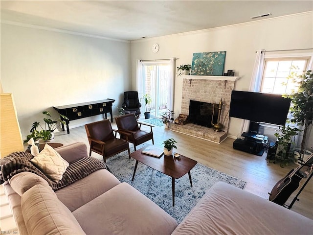 living area with a brick fireplace, wood finished floors, visible vents, and ornamental molding