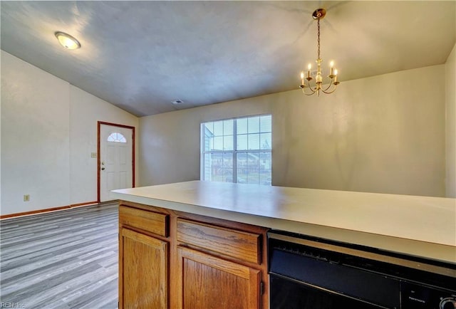 kitchen with baseboards, lofted ceiling, wood finished floors, hanging light fixtures, and a notable chandelier