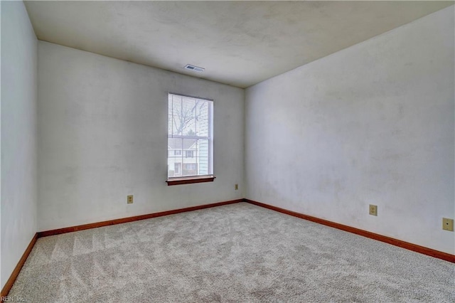 spare room with carpet flooring, baseboards, and visible vents