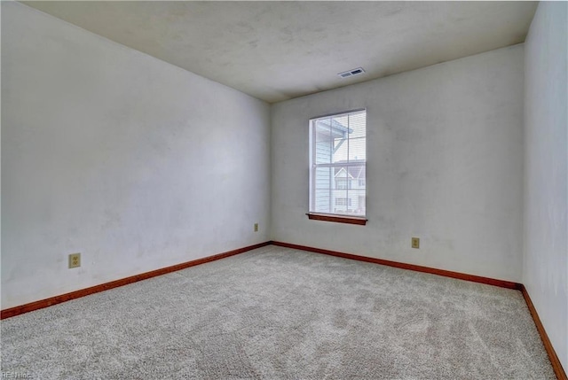 carpeted spare room with visible vents and baseboards