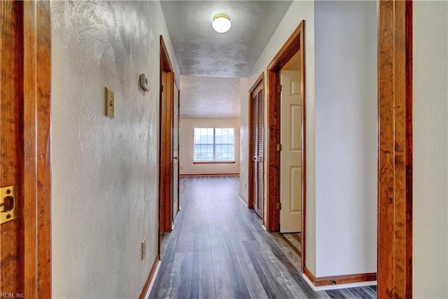 corridor with wood finished floors and baseboards