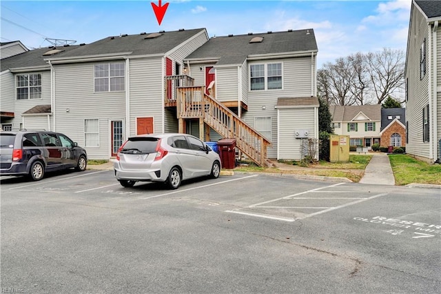 view of front of house with stairway, uncovered parking, and a residential view