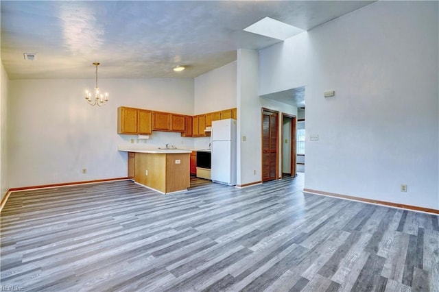 kitchen featuring a peninsula, freestanding refrigerator, light countertops, a notable chandelier, and open floor plan