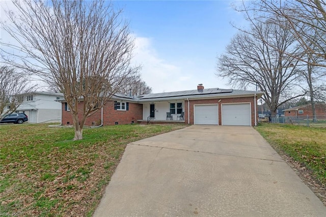 ranch-style home with solar panels, a front yard, an attached garage, and brick siding