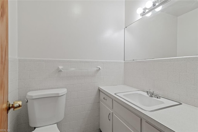 bathroom featuring tile walls, a wainscoted wall, toilet, and vanity