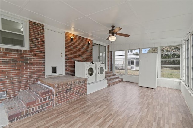 unfurnished sunroom with a fireplace, separate washer and dryer, and ceiling fan