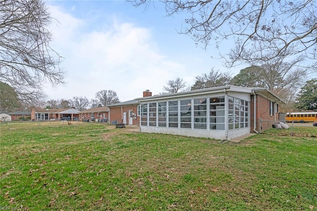 rear view of house featuring a yard, brick siding, and a sunroom