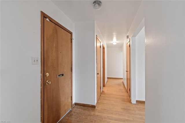 corridor featuring light wood-style floors and baseboards