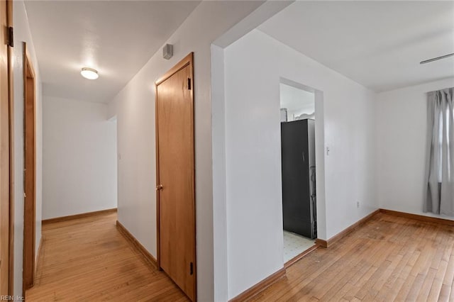 hallway featuring light wood-type flooring and baseboards