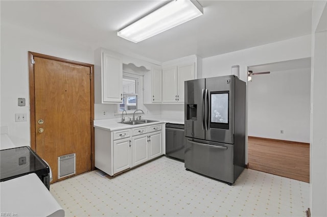 kitchen featuring light floors, light countertops, white cabinets, black appliances, and a sink