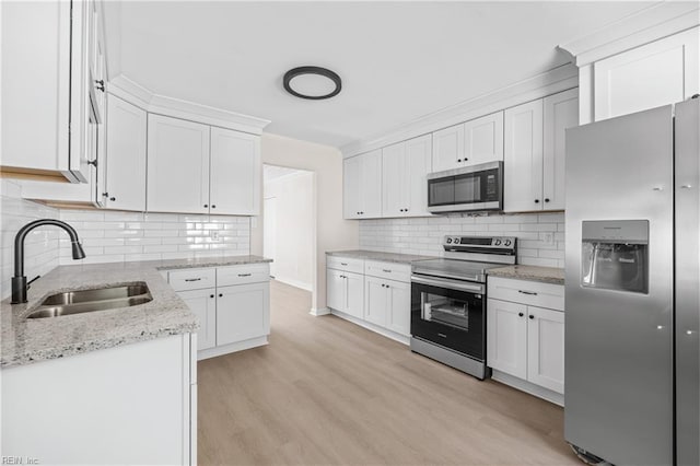 kitchen with a sink, stainless steel appliances, light wood-style floors, and white cabinets