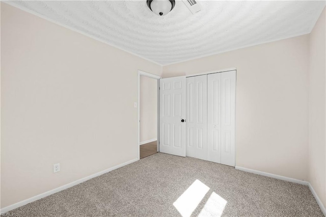 unfurnished bedroom featuring a closet, baseboards, carpet, and a textured ceiling