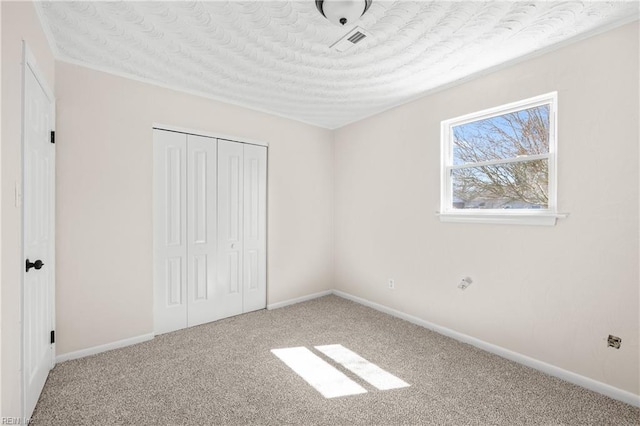 unfurnished bedroom with a closet, visible vents, baseboards, and carpet floors