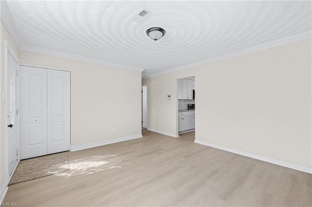 interior space featuring crown molding, light wood-style floors, visible vents, and baseboards