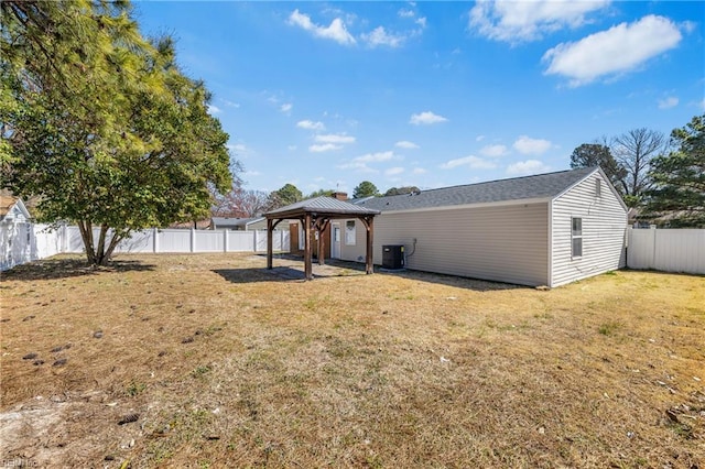 rear view of house featuring a gazebo, cooling unit, a lawn, and a fenced backyard