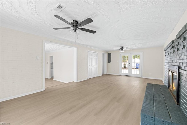 unfurnished living room with a fireplace, french doors, visible vents, and ceiling fan