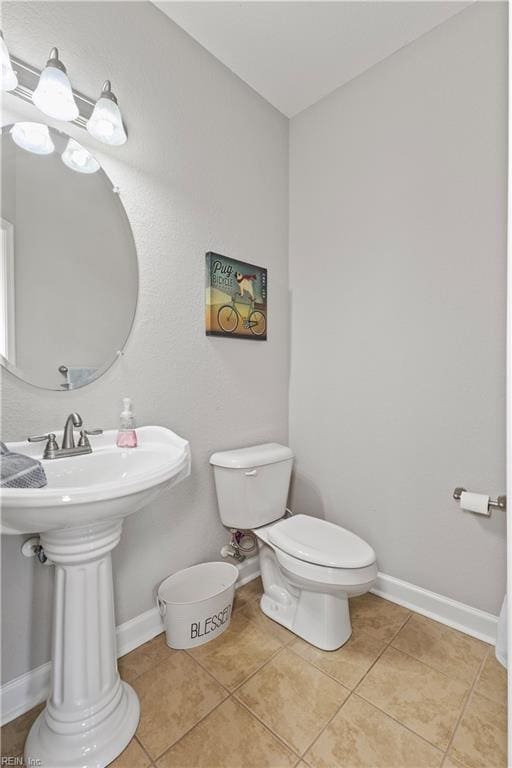 bathroom with a sink, baseboards, toilet, and tile patterned flooring