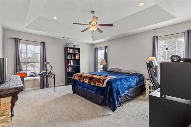 carpeted bedroom featuring a raised ceiling, recessed lighting, baseboards, and ceiling fan