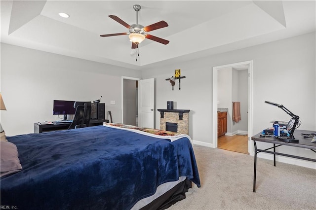 bedroom with a raised ceiling, a ceiling fan, ensuite bath, carpet, and baseboards